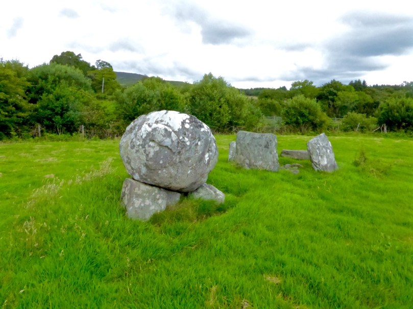 Boulder burial showing support stones. Five-stone circle in the background